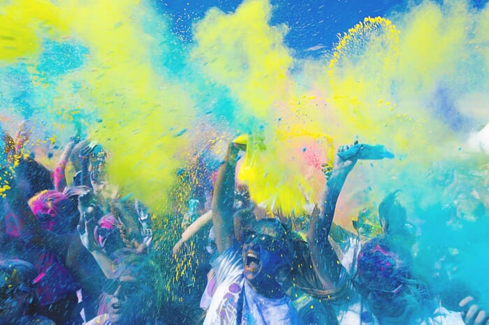 crowd with colourful yellow and blue powder