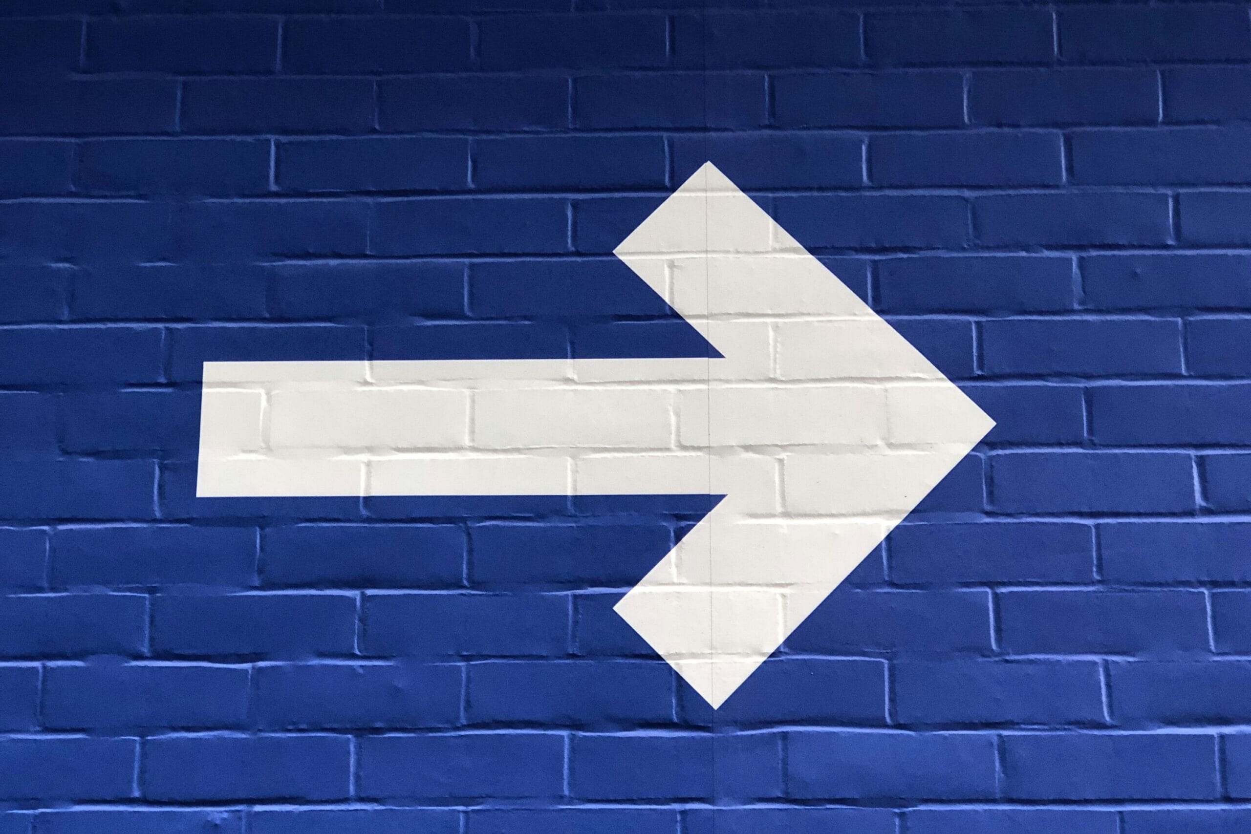 white arrow on blue background pointing forwards