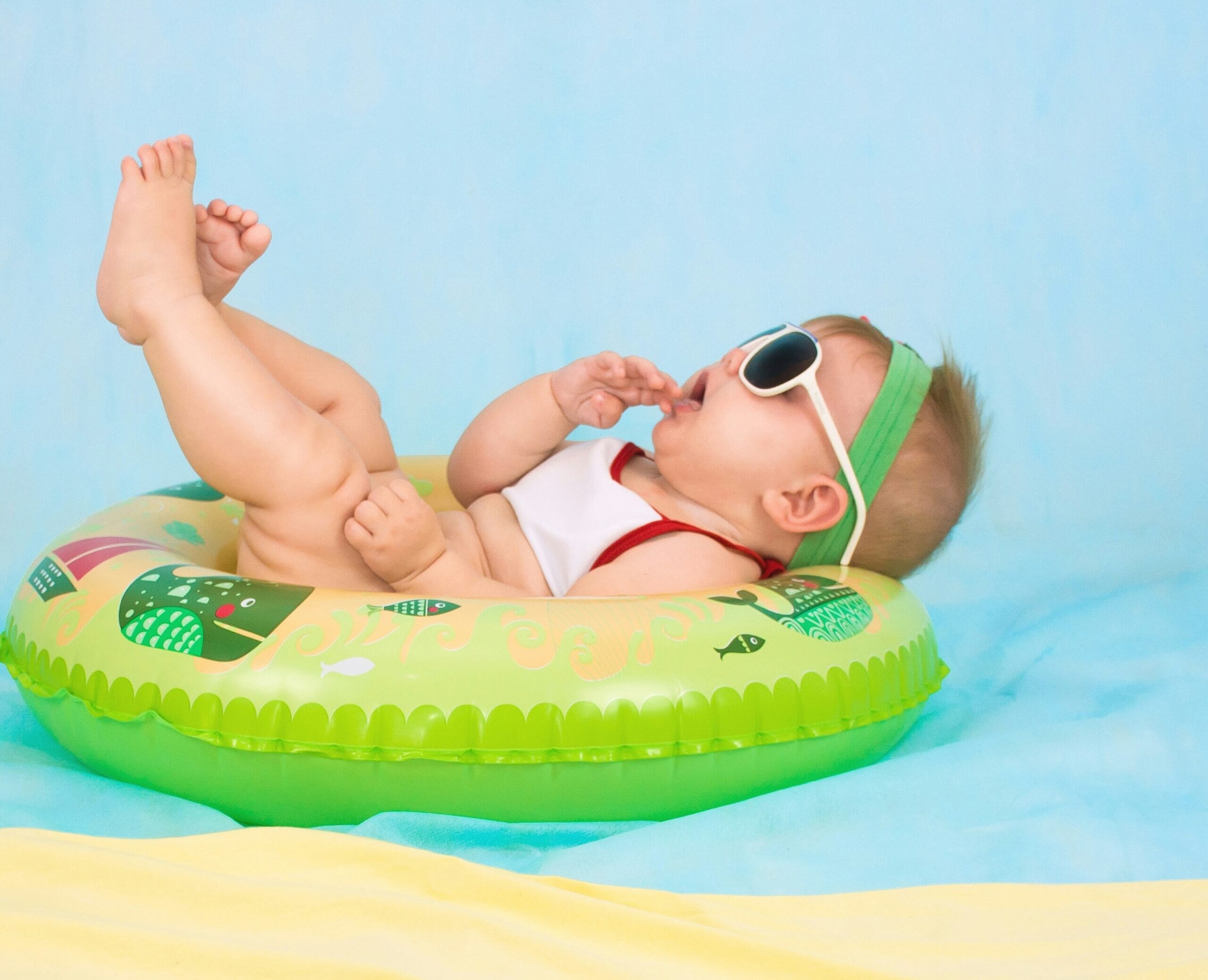 baby with sunglasses on floating in a rubber ring